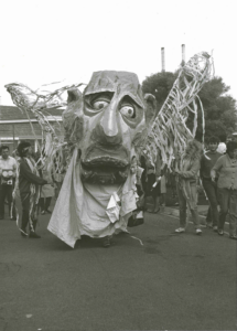 a large puppet is surrounded by people. 