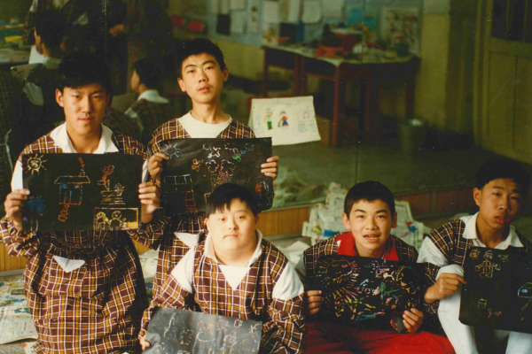 Boys at a school in China are holding up their drawings.