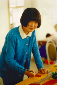 a young teenagers is painting in a classroom