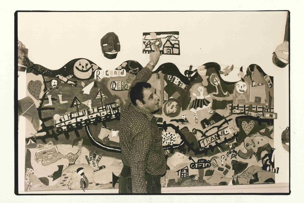 A man is pointing at a large mural.