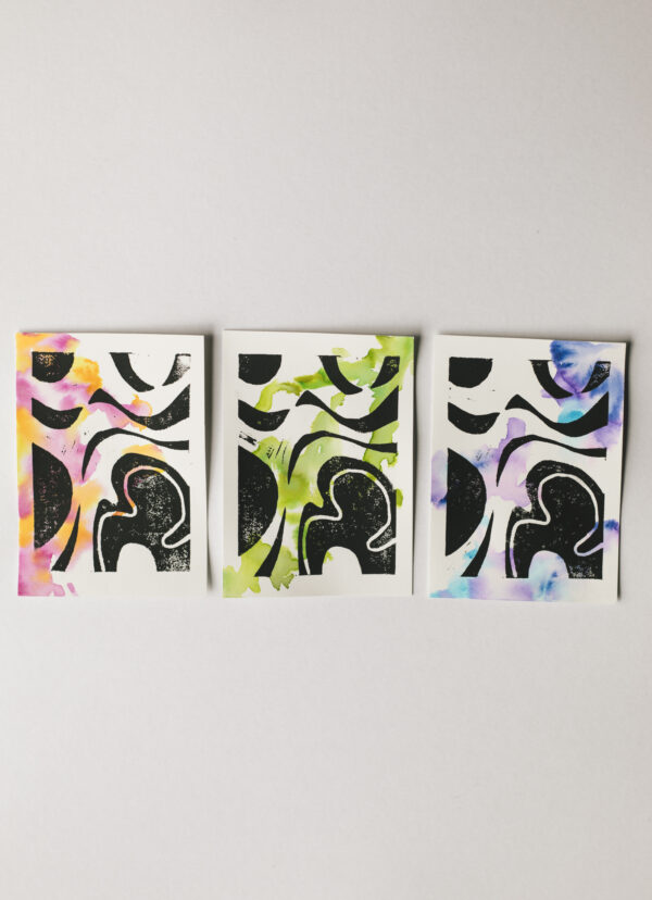 Set of 3 linocuts with colourful watercolour backgrounds. The colours are pink and orange on the left print, green in centre, and blue and purple on the right.