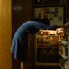 self portrait (me) - a woman leaning over to peer into the light illuminated fridge