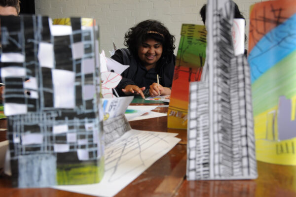 A person looking between paper models of buildings and skyscrapers.